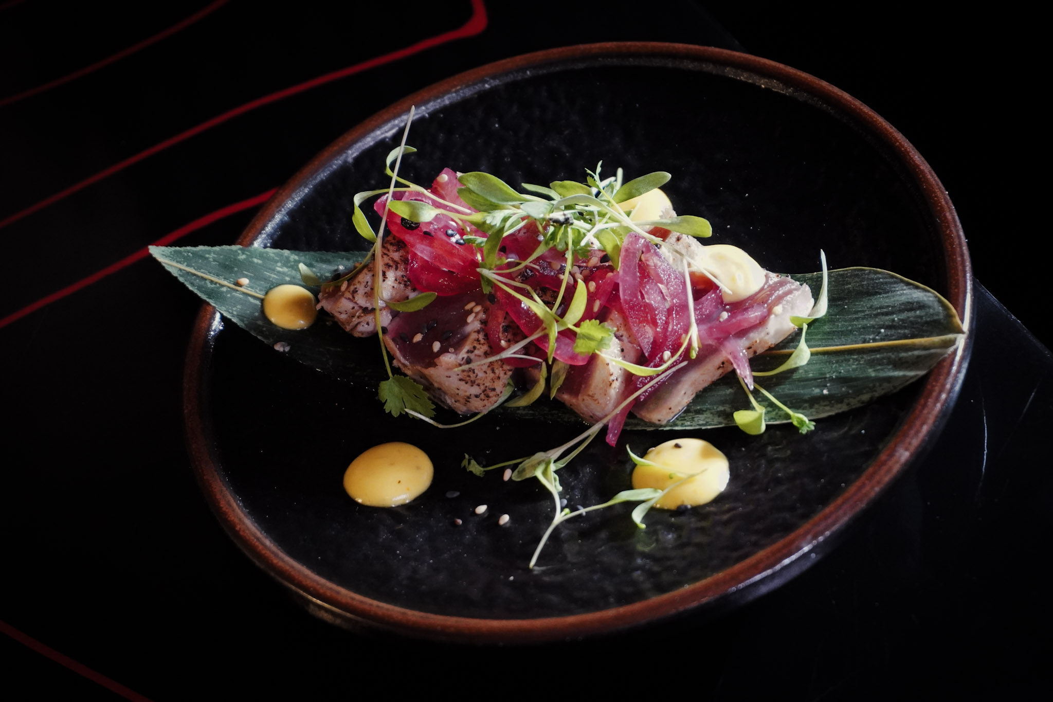 Seared tuna tataki plated with microgreens showcasing Japanese precision.